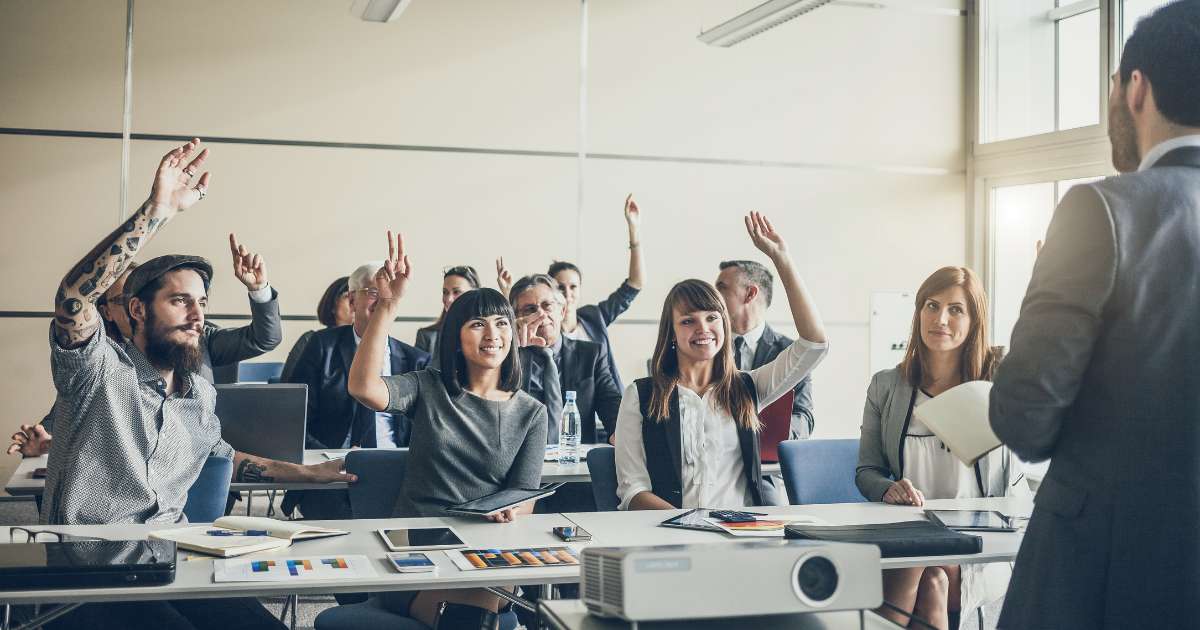 Apprenants levant la main pour répondre à une question posée par leur formateur